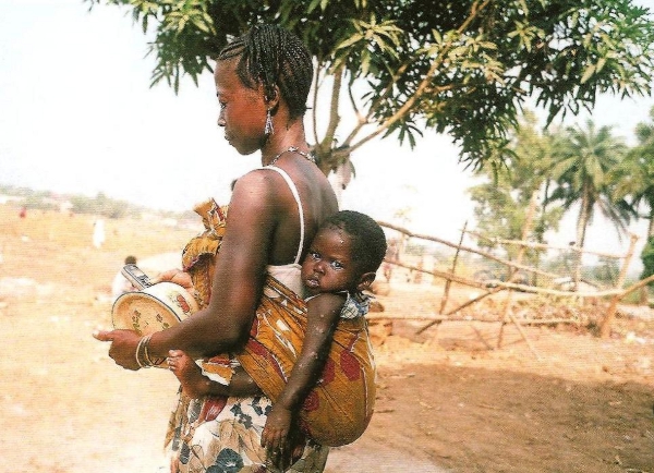 Νεαρή μητέρα η οποία συνδυάζει παρ΄ όλη την φτώχειά της, την παράδοση -μεταφέρει το παιδί της στην πλάτη της- και την τεχνολογία -κρατόντας το κινητό στο χέρι-.