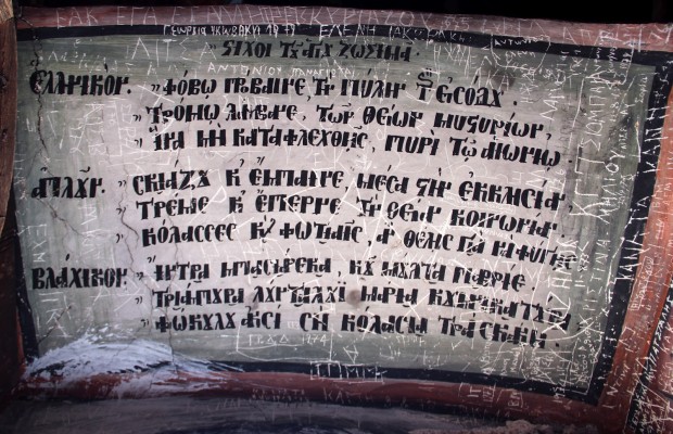 Η σημαντική ιστορική επιγραφή πάνω από την είσοδο της Ιεράς Μονής Αγίων Αποστόλων η οποία είναι γραμμένη σε τρεις γλώσσες. Αρχαία ελληνικά, νέα ελληνικά και βλάχικα (αρωμουνικά) 
