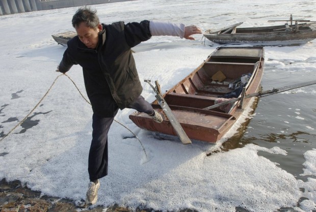 a-fisherman-jumps-from-his-boat-to-the-bank-after-fishing-in-the-morning-at-a-polluted-river-in-hefei-in-east-chinas-anhui-province-march-8-2007