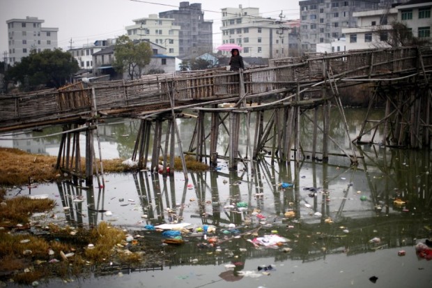 a-woman-walks-on-a-bridge-over-a-polluted-river-at-a-suburban-area-of-wenzhou-in-zhejiang-province