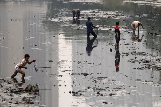 fishermen-walk-through-the-muddy-bottom-of-a-polluted-canal-collecting-fish-in-central-beijing