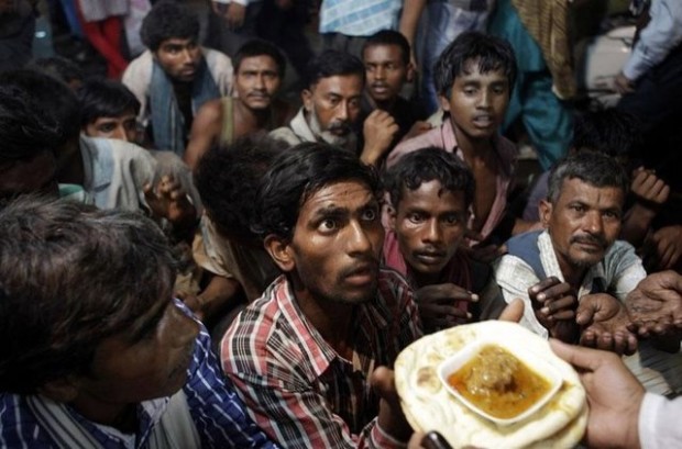  Ινδοί άστεγοι άνδρες περιμένουν να πάρουν τρόφιμα που τους διανέμονται δωρεάν έξω από ένα τζαμί στο Νέο Δελχί , ​​Ινδία
