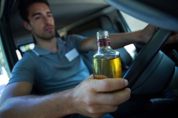 Slumped man holding alcohol bottle while driving car
