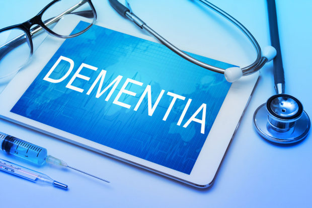 Dementia word on tablet screen with medical equipment on background