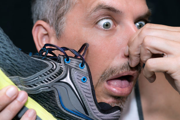 Close-up of a man gagging after smelling his running shoe.