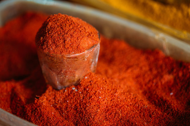 Close View Of Glass With Powdered Paprika Or Cayenne Pepper, Standing In The Heap Of Bright Red Fragrant Spice On Sale At The East Market, Bazaar.